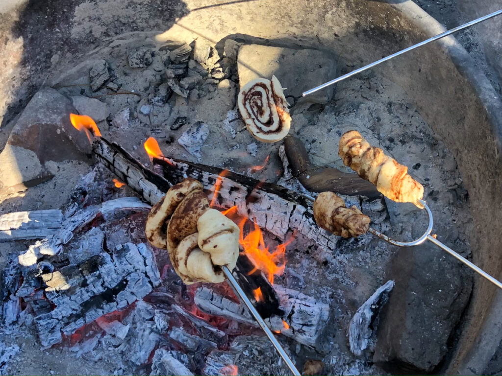 Cooking cinnamon rolls on a stick over the fire is one of our favorite easy camping meals
